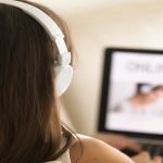 Estudante visualiza conteúdo educacional em tela de notebook com fones de ouvido