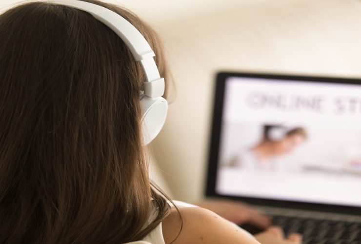 Estudante visualiza conteúdo educacional em tela de notebook com fones de ouvido